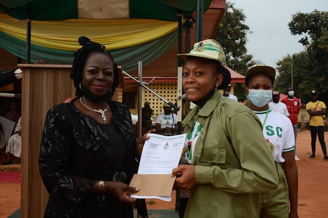 A physically challenged Corps Member, Adama, Ojodumine Eunice receiving Letter of Commendation from the State Coordinator, Mrs. Victoria Nnenna Ani for participating in all camp activities during the 2022 Batch 'B' (Stream II) orientation course.