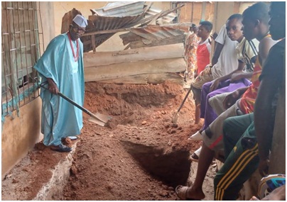 Mr Kayode Olarewaju performing the dust-to-dust rites on his father at the graveside			Photo: Stephen Olajide